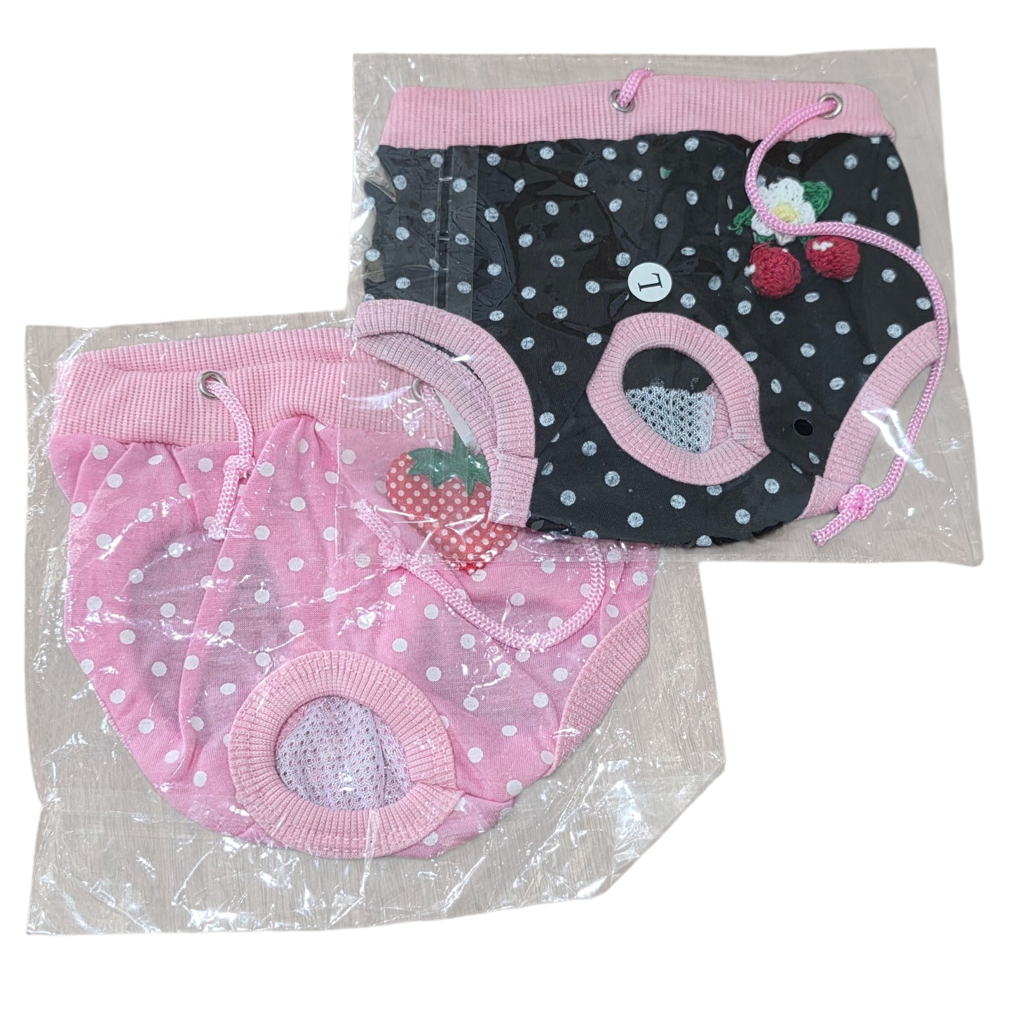 Two pairs of polka dot dog pants, one pink and one black with white dots, on a white background.