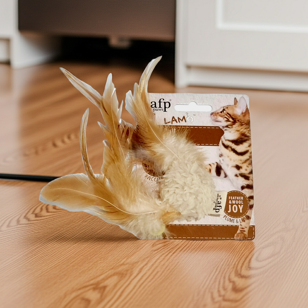 AFP Lambswool Cat Ball with Soundchip Cat toy with feathers on a wooden floor, featuring AFP packaging.