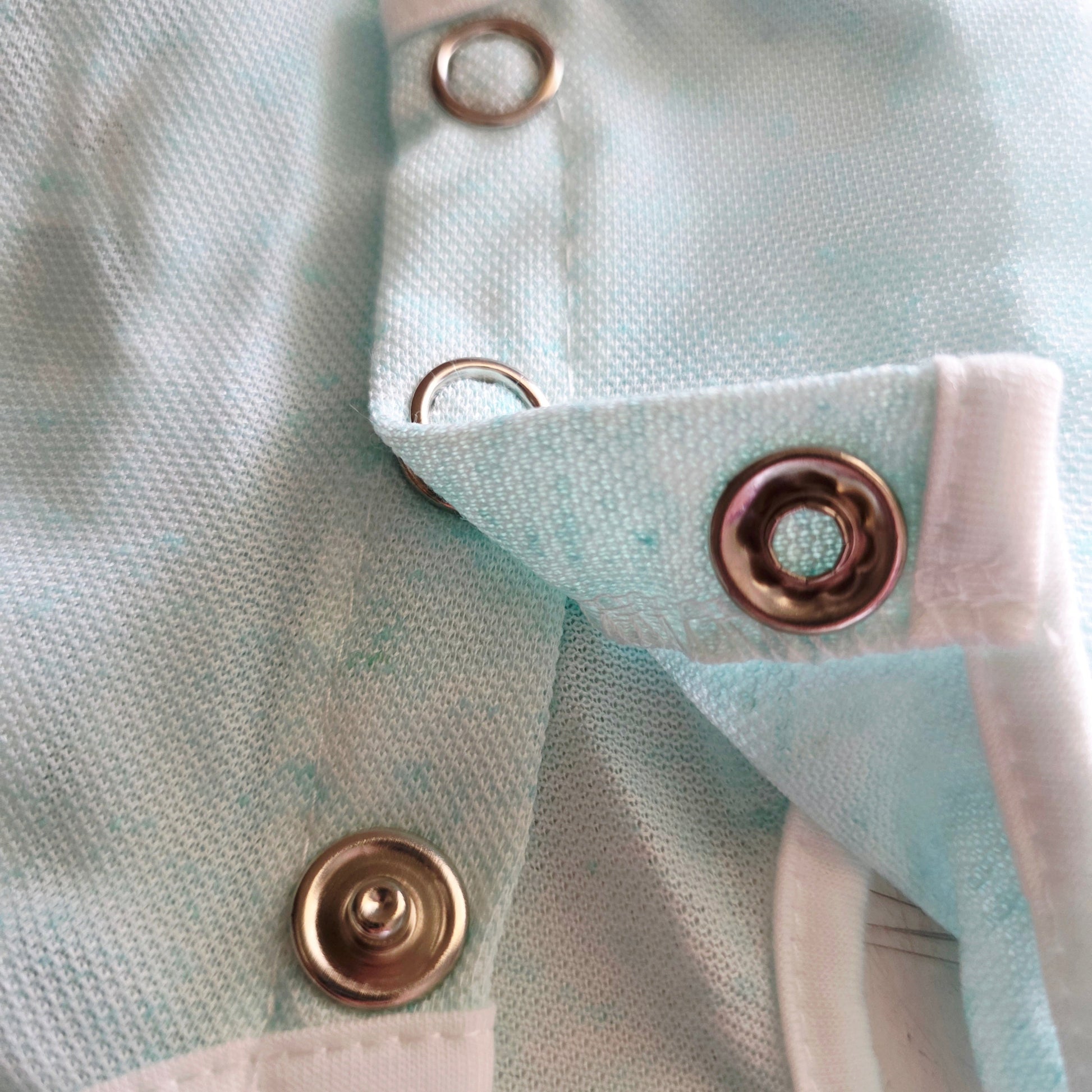 Close-up of light blue cat recovery suit with large snap buttons