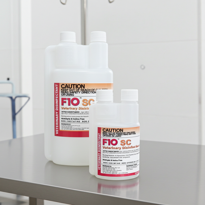 Two white plastic bottles of FIO SC Veterinary Disinfectant and Antiseptic solution, one larger bottle and one smaller bottle, standing on a reflective metal surface against a light gray background.