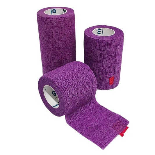 Three rolls of purple Genia Bitter Cohesive Bandage tape with one roll partially unrolled, showing the textured fabric and red brand tab on a white background.