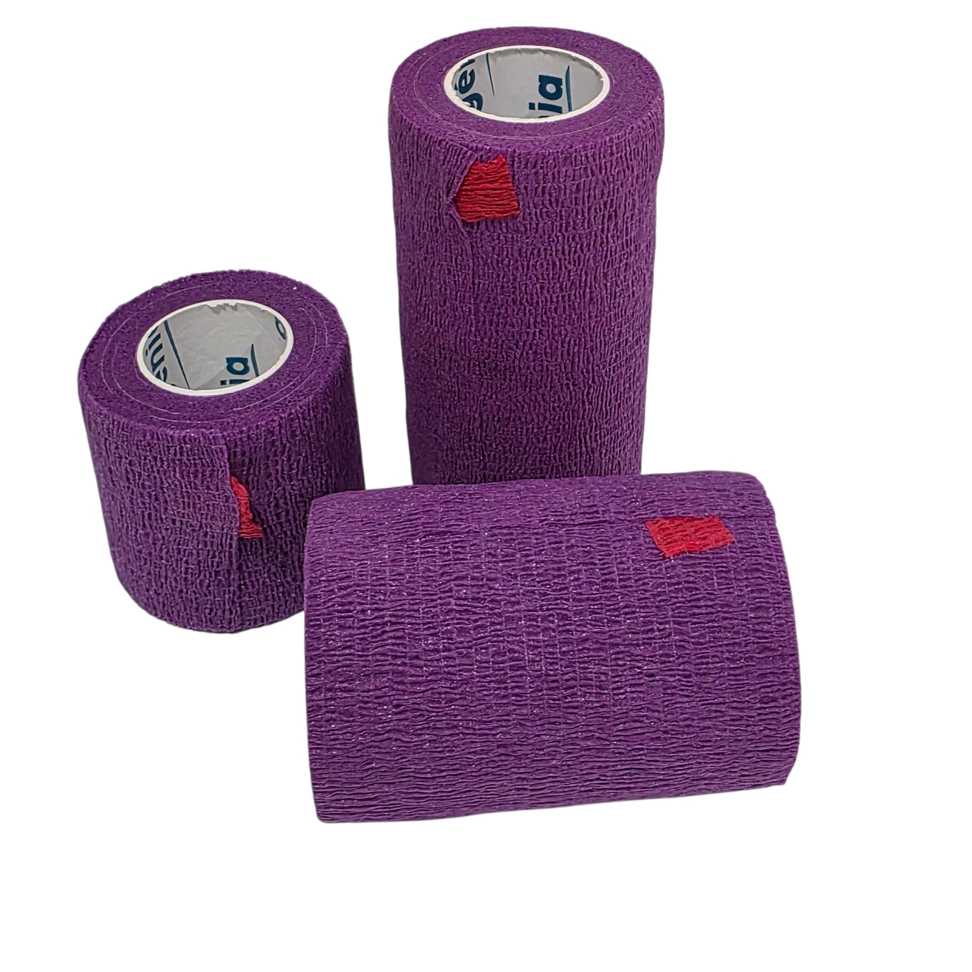 Three rolls of textured purple Genia Bitter Cohesive Bandage with small red triangular tabs, shown on a plain white background.