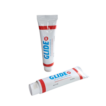 Two tubes of Glide semen safe lubricant in a resealable tube. The packaging is predominantly white with red and blue accents, and text indicates the product is a lubricant.