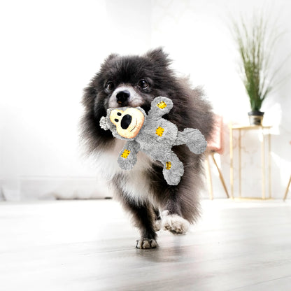 Dog holding a gray KONG Wild Knots bear toy indoors