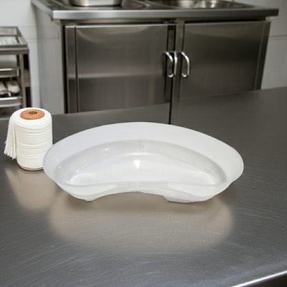 Kidney dish on a stainless steel surface with hospital cupboards in the background