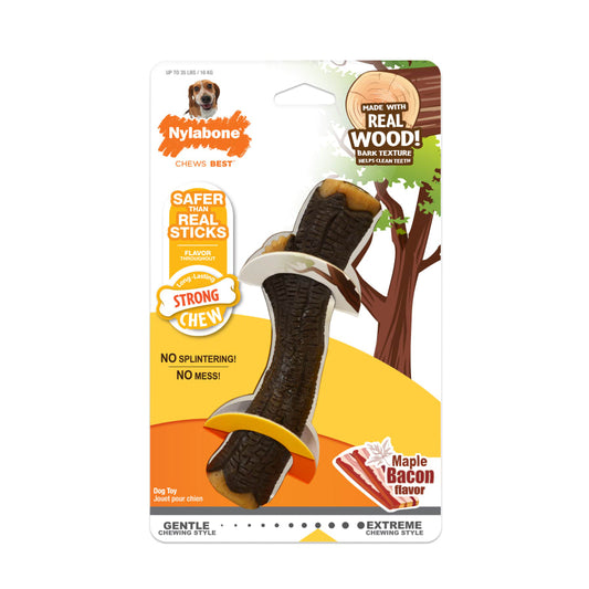 A packaged Nylabone Strong Chew dog stick toy in Maple Bacon flavor, designed to resemble a wood stick, with no splintering and no mess promised. The packaging features a yellow background with a cartoon dog and a tree, highlighting the product's natural wood element.