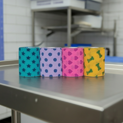 Four rolls of colorful Petflex Patterned Cohesive Bandage on a metallic surface with a blurred background.