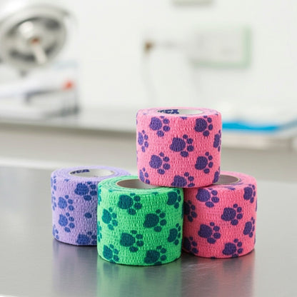 Four rolls of Petfex Paw Cohesive bandage stacked on a reflective metal surface in a blurred clinical setting.
