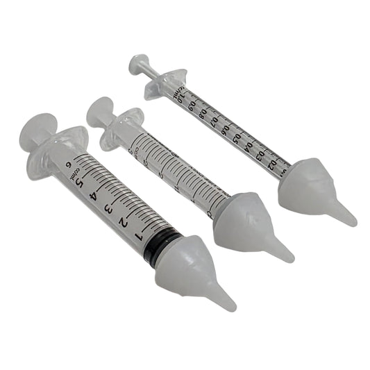 Three clear plastic syringes with SuckleSoft Teats arranged diagonally on a white background.