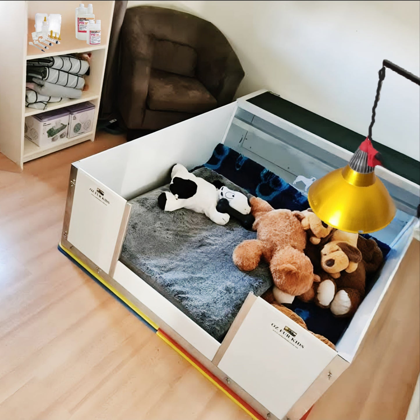 Whelping box with plush toys on a wooden floor